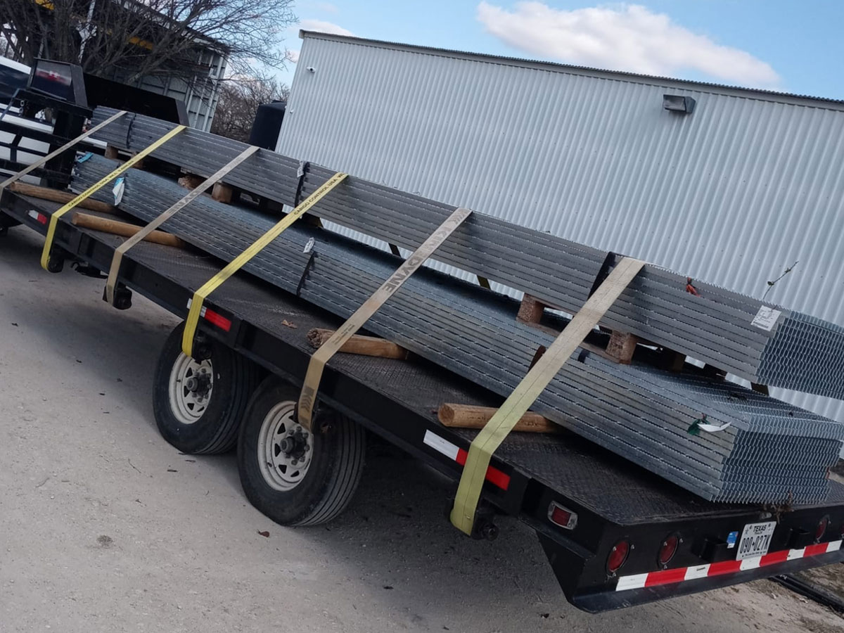 Flatbed trailer loaded with strapped metal grating panels ready for delivery