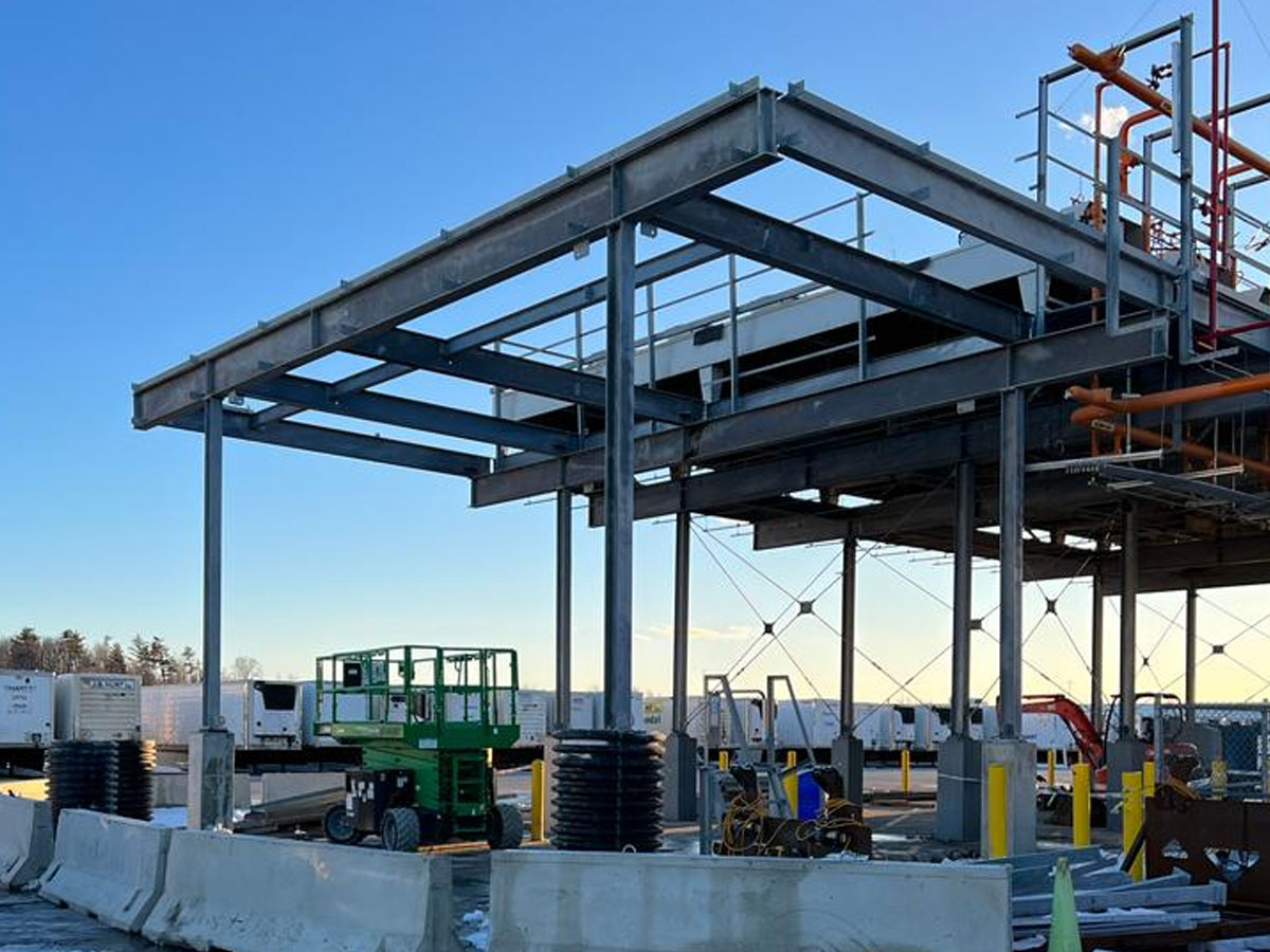 Steel beam framework under construction with crane and scissor lift at building site
